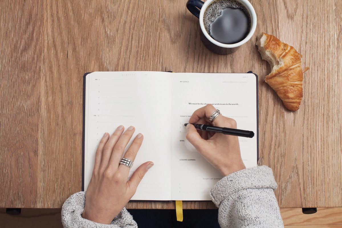 A person writing on a document with a pen.