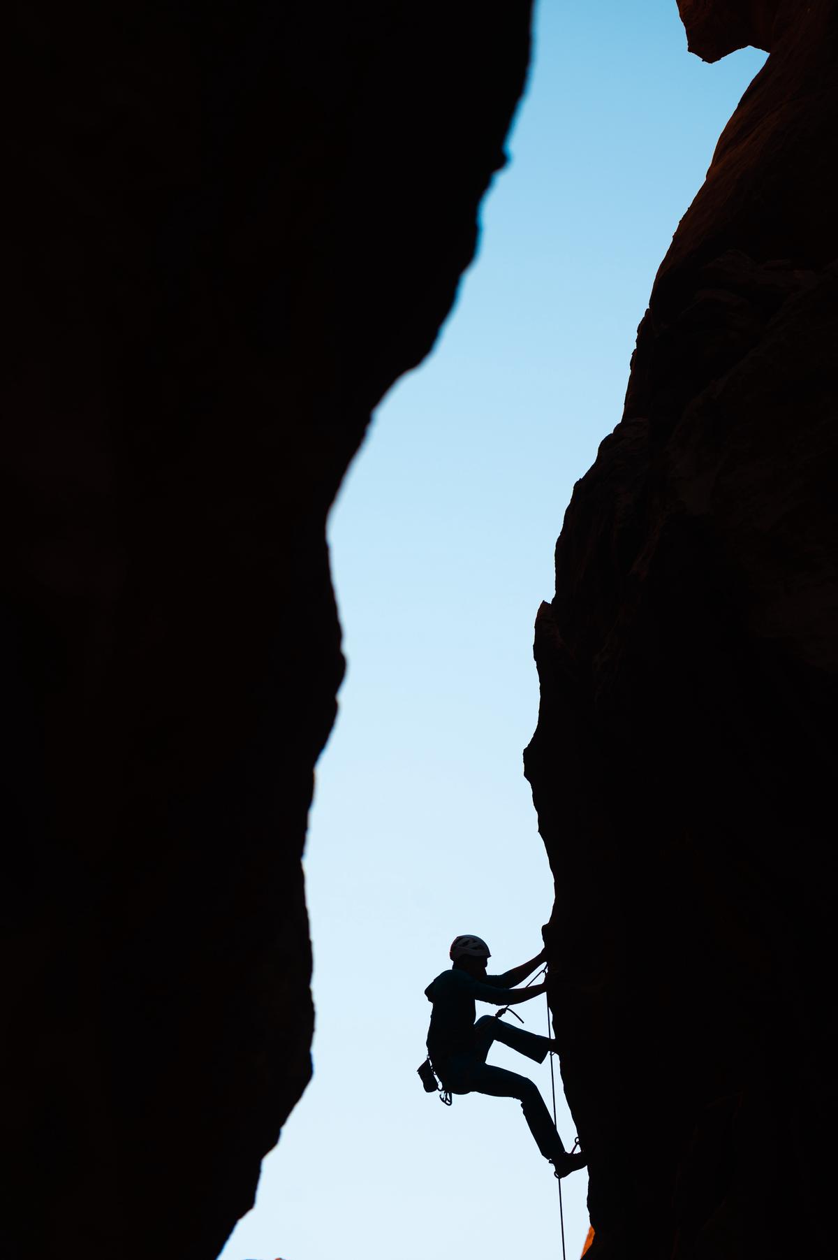 A person climbing a mountain, representing the challenges and growth of professional diversity.