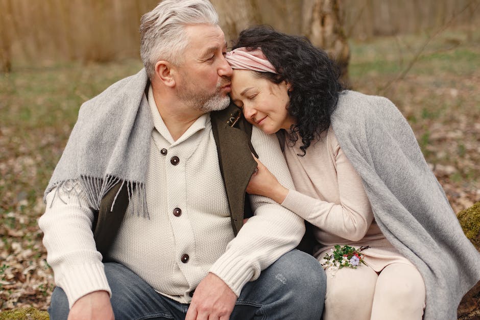Image of a happy retired couple embracing in a park surrounded by flowers and trees